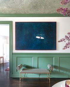 a living room with green paneling and a painting on the wall above a bench