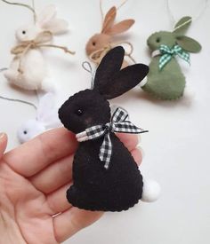 a hand is holding an ornament that looks like a black bunny with a bow on it