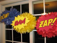 some paper decorations are hanging on the window sill in front of a door that says powi, bam, zap and powi