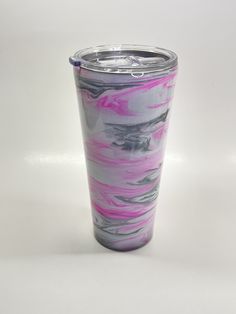 the tumbler cup is painted with pink and grey swirls on it's side