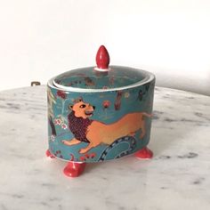 a ceramic container with a lion on it sitting on a marble countertop next to a white wall