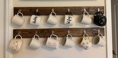 coffee mugs are hanging on the wall with hooks