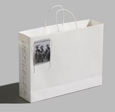 a white shopping bag with an old photo on the front and bottom, attached to a string