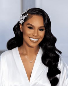 a woman with long black hair wearing a white dress and smiling at the camera she is wearing a diamond tiara