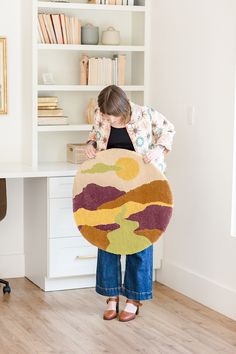 a woman is holding a rug in front of her face while standing at a desk