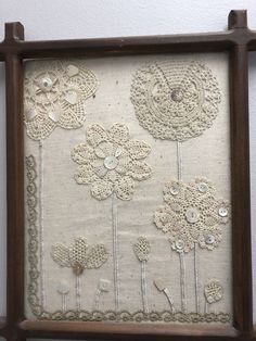 an old frame with some flowers and buttons on the front is hung up against a wall