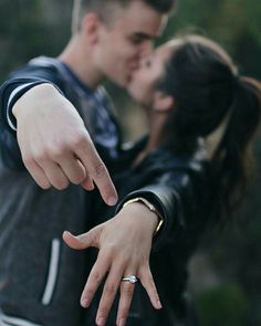 a young man and woman are kissing with their fingers pointing at the camera while holding each other's hand