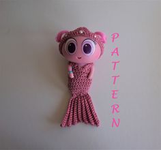 a pink crocheted mermaid doll laying on top of a white surface with the word pattern written across it