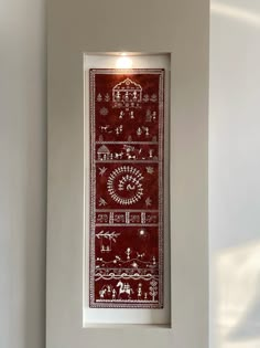 a red and white wall hanging on the side of a wall next to a window