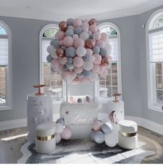 a bunch of balloons that are on top of a table in front of some windows