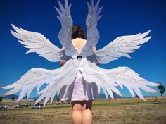 a woman standing in front of a large paper angel