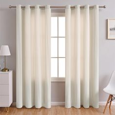 a white curtain hanging in front of a window next to a chair and side table