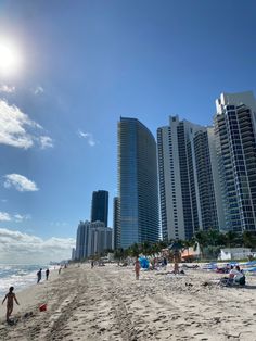 people are on the beach in front of high rise buildings