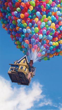 a large group of balloons being released into the sky by a house on stilts