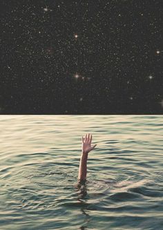 a person in the water with their hand up to the sky and stars above them