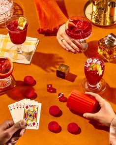 two people playing cards at a table with drinks and candies in front of them