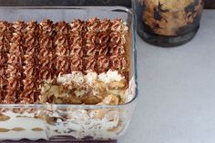 a casserole dish filled with food sitting on top of a counter next to a glass container