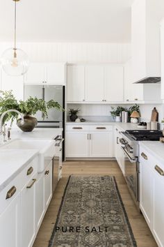 a kitchen with white cabinets and an area rug on the floor in front of the stove