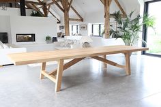 a large wooden table sitting inside of a living room next to a white couch and window