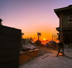 the sun is setting behind a building with construction equipment on the ground in front of it