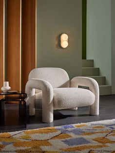 a white chair sitting on top of a wooden floor next to a wall mounted light