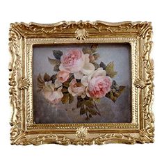 an ornate gold frame with pink roses in it on a white wall behind the painting