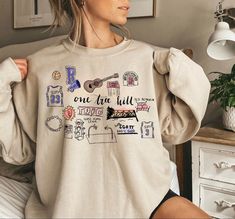 a woman sitting on a bed wearing a sweatshirt with the words one true full printed on it