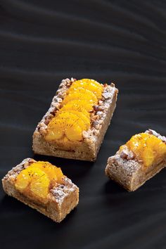 three pieces of bread with oranges on them sitting next to each other in front of a black background