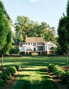 a large white house surrounded by lush green trees