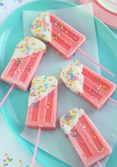 pink popsicles with white frosting and sprinkles on a blue plate