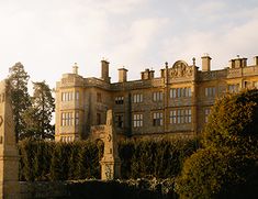 an old building with a clock tower in front of it and hedges around the perimeter