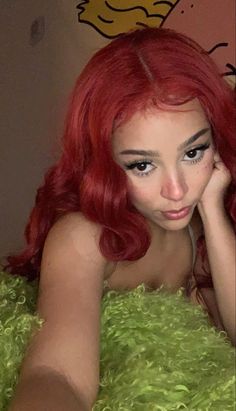 a woman with red hair laying on top of a fluffy green bed covered in fur