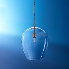 a clear glass light bulb hanging from a chain on a blue background with the sky in the background