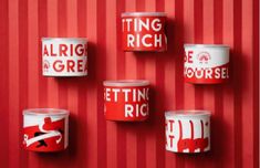 red and white tins on a wall with the words being rich written in them