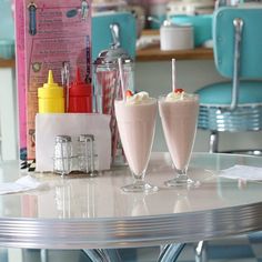 two drinks are sitting on a table in front of some candy bars and ice cream