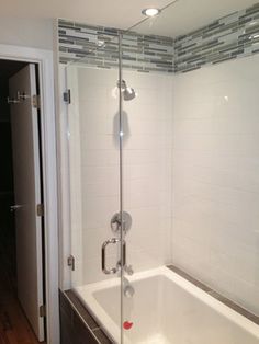 a bath tub sitting next to a walk in shower with a glass door and tiled walls