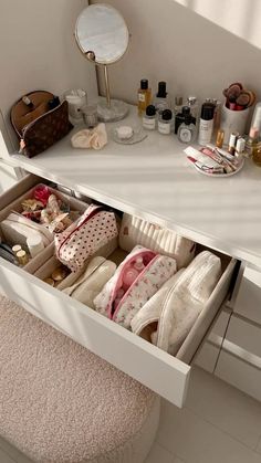 an open drawer in the middle of a white vanity with cosmetics and other items on it