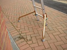 a ladder leaning up against a brick wall next to a sidewalk with a fire hydrant in the background