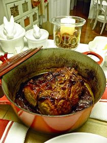 a pot filled with meat sitting on top of a table next to plates and utensils