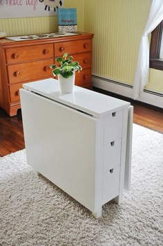 a white cabinet with three drawers and a potted plant sitting on top of it