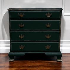 a green chest of drawers sitting on top of a hard wood floor next to a white wall