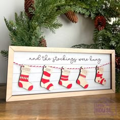 a christmas card with stockings hanging from the clothes line and pine cones in the background