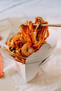 a close up of a box of food with noodles and shrimp in it on a table