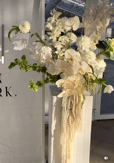 a vase filled with white flowers sitting on top of a table next to a sign