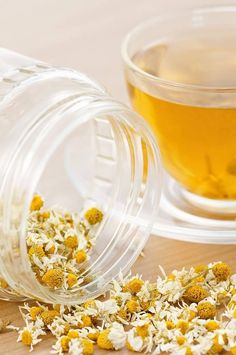 a glass jar filled with flowers next to a cup of tea