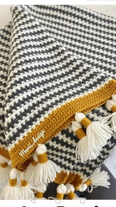 a crocheted blanket with tassels on it