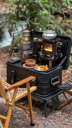 an outdoor stove with food cooking on it in the woods next to a camping chair