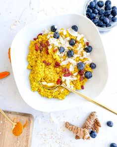 a bowl filled with oatmeal and blueberries next to some sliced ginger