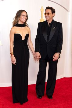 two people standing next to each other on a red carpet at an oscars event