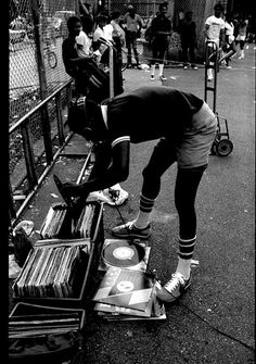 a woman is bending over to pick up record's from the rack on the street